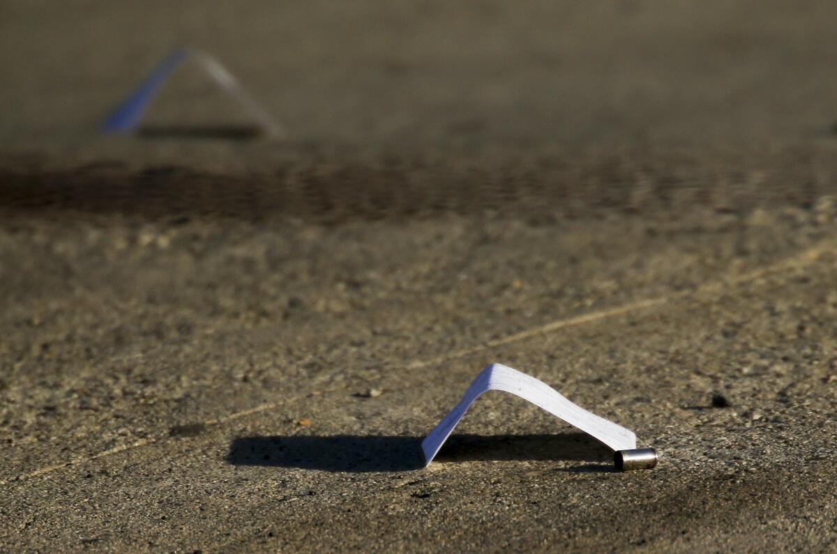 Evidence markers stand next to shell casings in a driveway in the Watts neighborhood of Los Angeles on July 26, 2016.