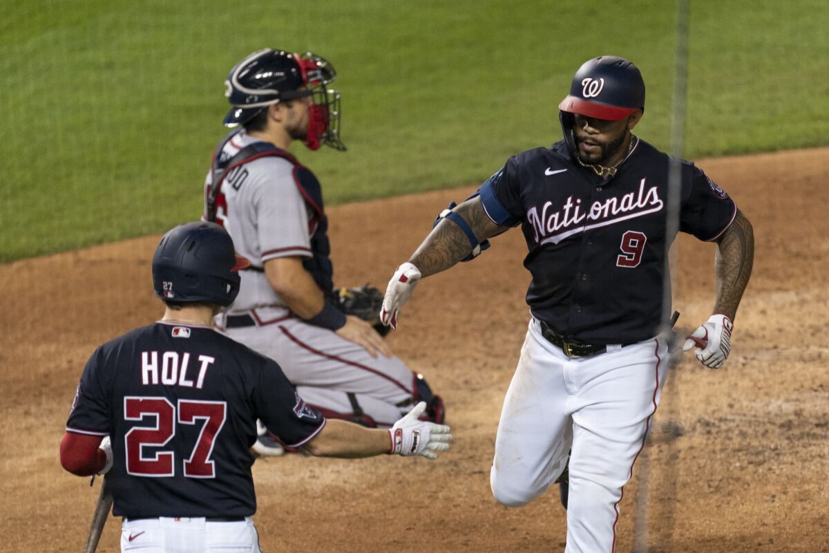 Washington Nationals' Eric Thames (9) is congratulated by Brock Holt (27) after hitting a home run during the fifth inning of the team's baseball game against the Atlanta Braves in Washington, Friday, Sept. 11, 2020. (AP Photo/Manuel Balce Ceneta)