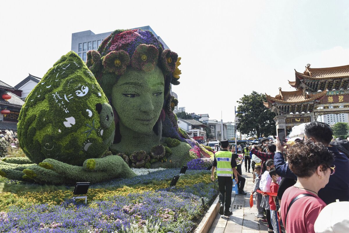 Tourists pass by a floral decoration celebrating the U.N. Biodiversity Conference (COP 15) in a park in Kunming, the host city, in southwestern China's Yunnan province, on Oct. 2, 2021. China has pledged $230 million to establish a fund to protect biodiversity in developing countries. President Xi Jinping made the announcement at a U.N. conference on biodiversity held on Tuesday, Oct. 12, 2021 in Kunming, China. (Chinatopix via AP)