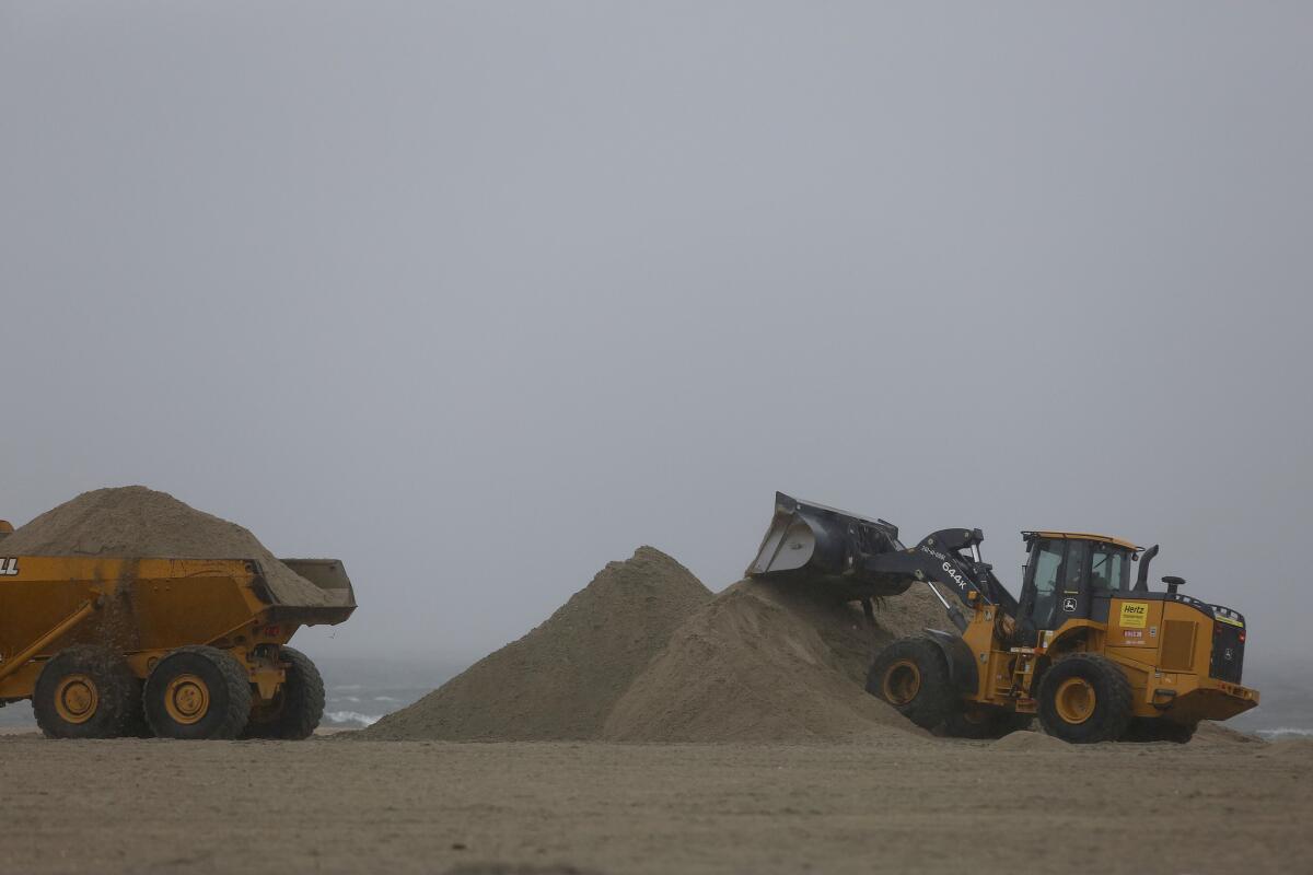 Earthmoving equipment move beach sand to protect vulnerable areas from flooding in rainy weather during the first big storm in what is predicted to be a strong El Ni?o event in Southern California.