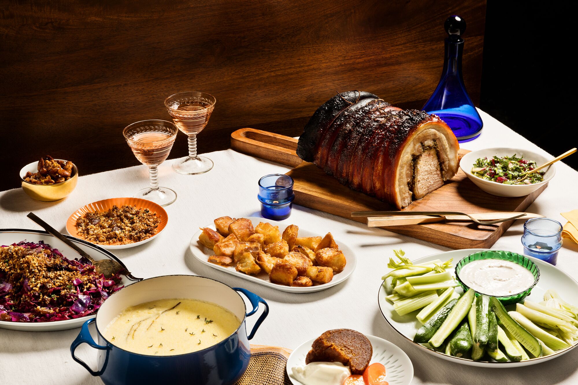 A holiday table with a feast of porchetta, polenta, roasted potatoes and more.