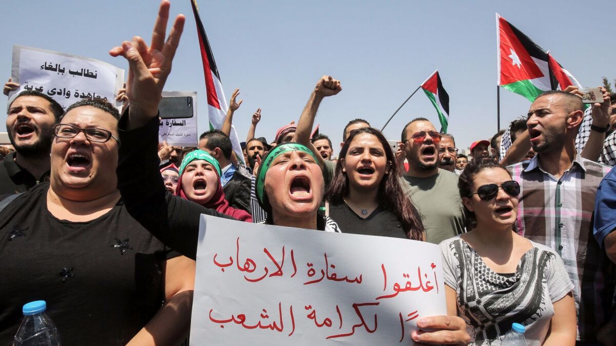 A Jordanian protester flashes the victory gesture as she holds a sign calling for closing down the Israeli Embassy in the capital, Amman, on July 28, 2017.