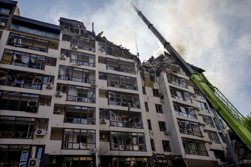 A crane reaches into the crushed top of a residential building in Kyiv.