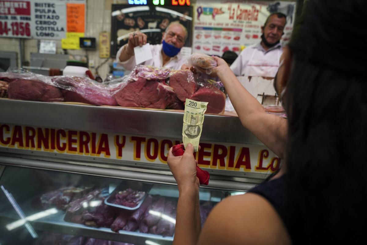 Un cliente paga con un billete de 200 pesos (unos 10 dólares) para comprar carne en el Mercado 