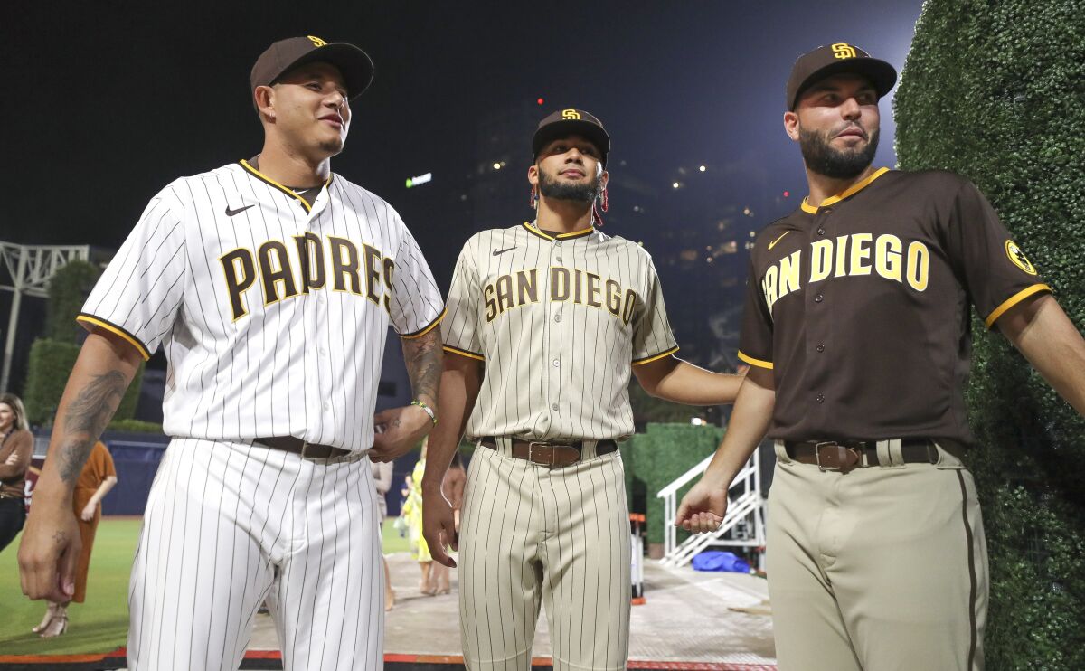 Manny Machado, left, Fernando Tatis Jr., center, and Eric Hosmer wear the Padres' new brown uniforms at an unveiling event.