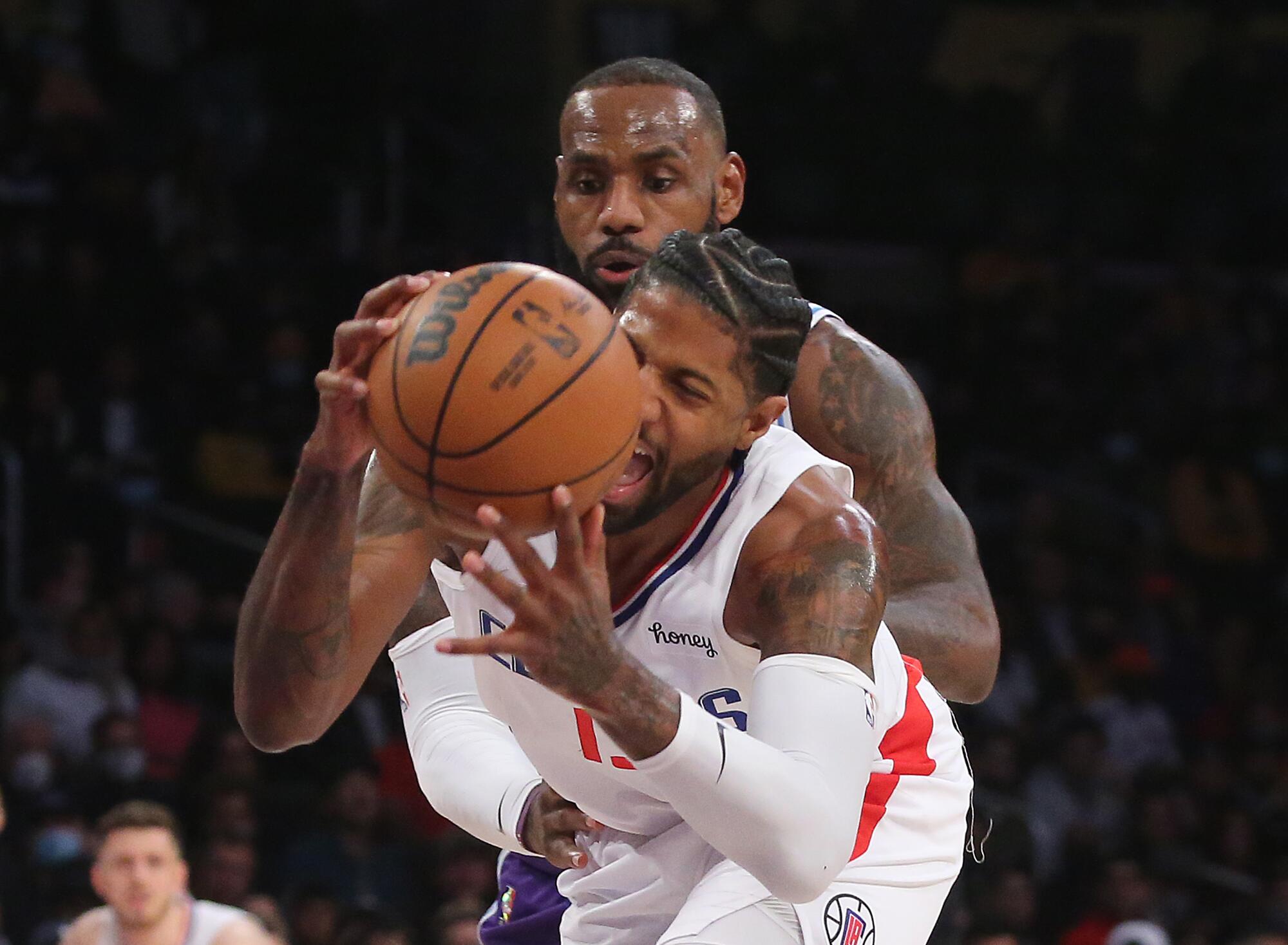 Clippers forward Paul George gets fouled by Lakers forward LeBron James.