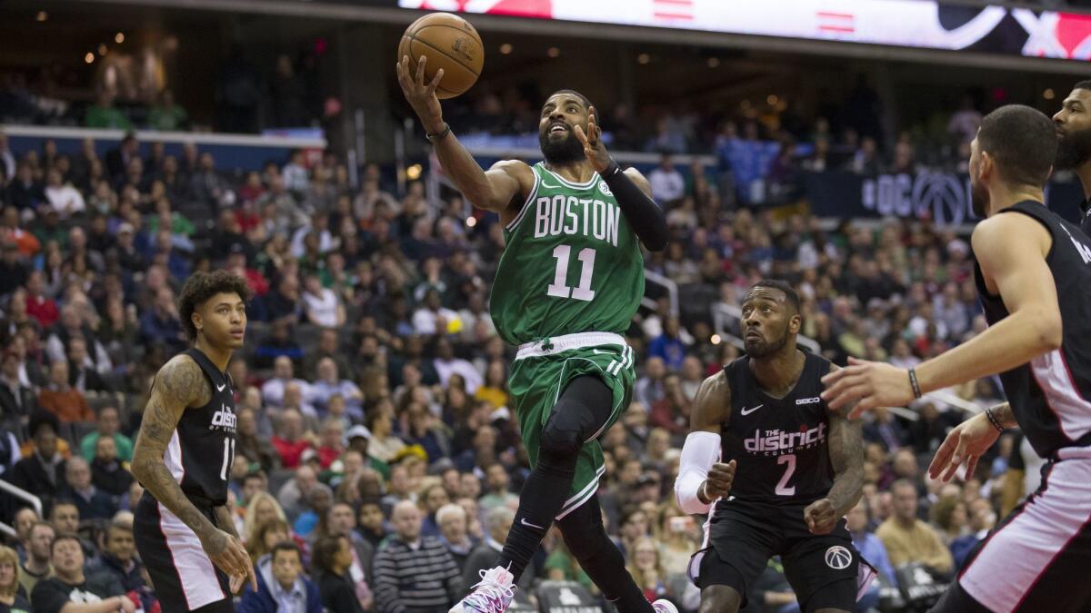 Boston Celtics guard Kyrie Irving (11) shoots between Washington Wizards forward Kelly Oubre Jr. (12), guard John Wall (2), and guard Austin Rivers, right, during the second half.