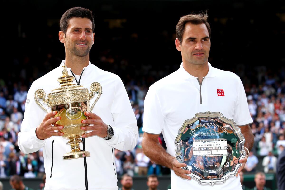 Novak Djokovic of Serbia and Roger Federer of Switzerland pose for a photo with their trophies after Men's Singles final against Roger Federer of Switzerland during Day thirteen of The Championships - Wimbledon 2019 at All England Lawn Tennis and Croquet Club on July 14, 2019 in London, England.