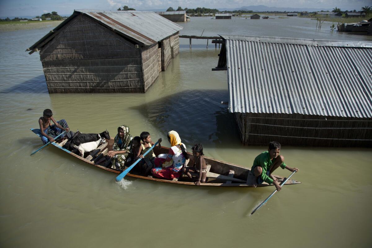 In this 2016 photo, flood-affected family travels on a boat in northeastern India.