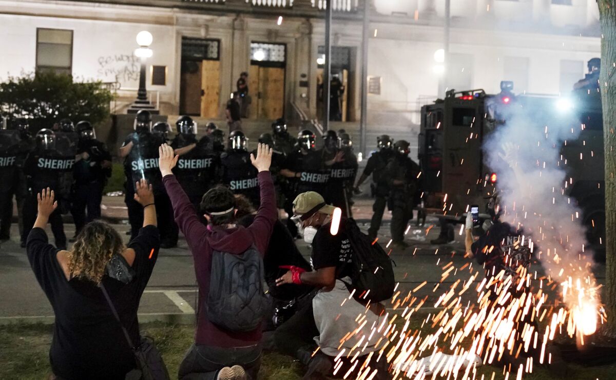 Police attempt to push back protesters outside the Kenosha County Courthouse, late Monday, Aug. 24, 2020, in Kenosha, Wis