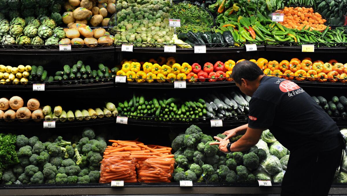 A produce clerk arranges vegetables at a Ralph's grocery store in downtown Los Angeles.