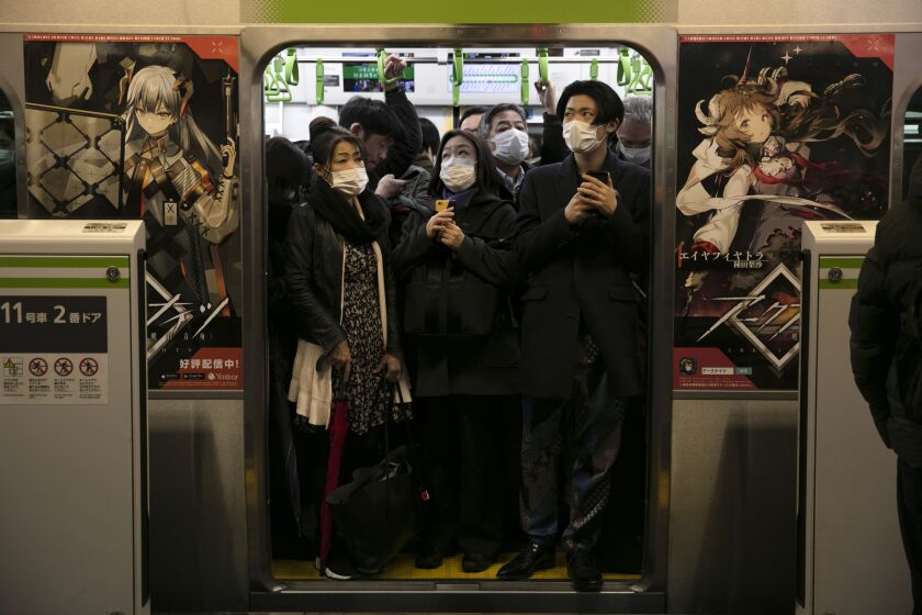 FILE - In this March 2, 2020, file photo, commuters wearing masks stand in a packed train at the Shinagawa Station in Tokyo. When the Japanese government declared an emergency to curb the spread of the coronavirus earlier April and asked people to work from home, crowds rushed to electronics stores. Many Japanese lack the basic tools needed to work from home. Contrary to the ultramodern image of Japan Inc. with its robots, design finesse and gadgetry galore, in many respects the country is technologically challenged. (AP Photo/Jae C. Hong, File)