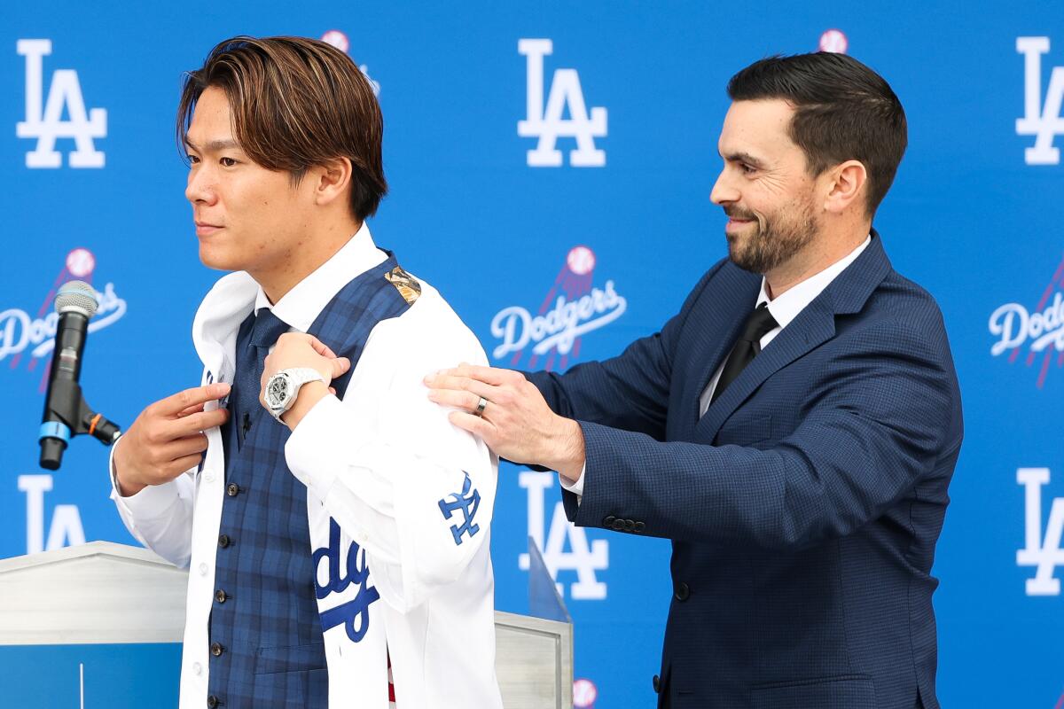 General manager Brandon Gomes puts a Dodgers Jersey on Yoshinobu Yamamoto.