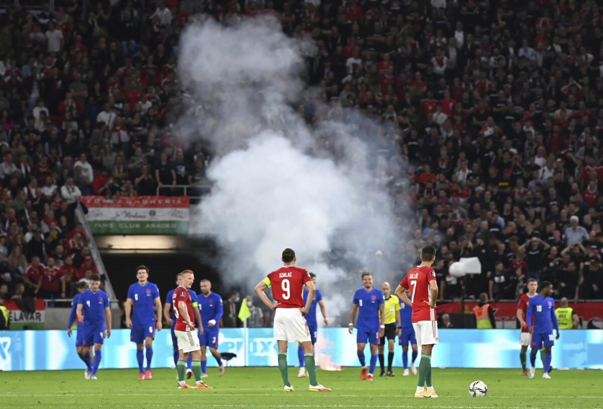 Players wait after a flare was thrown on the field after the third goal England scored, during the World Cup 2022 group I qualifying soccer match between Hungary and England, at the Puskas Ferenc Arena, in Budapest, Hungary, Thursday, Sept. 2, 2021. (Tibor Illyes/MTI via AP)