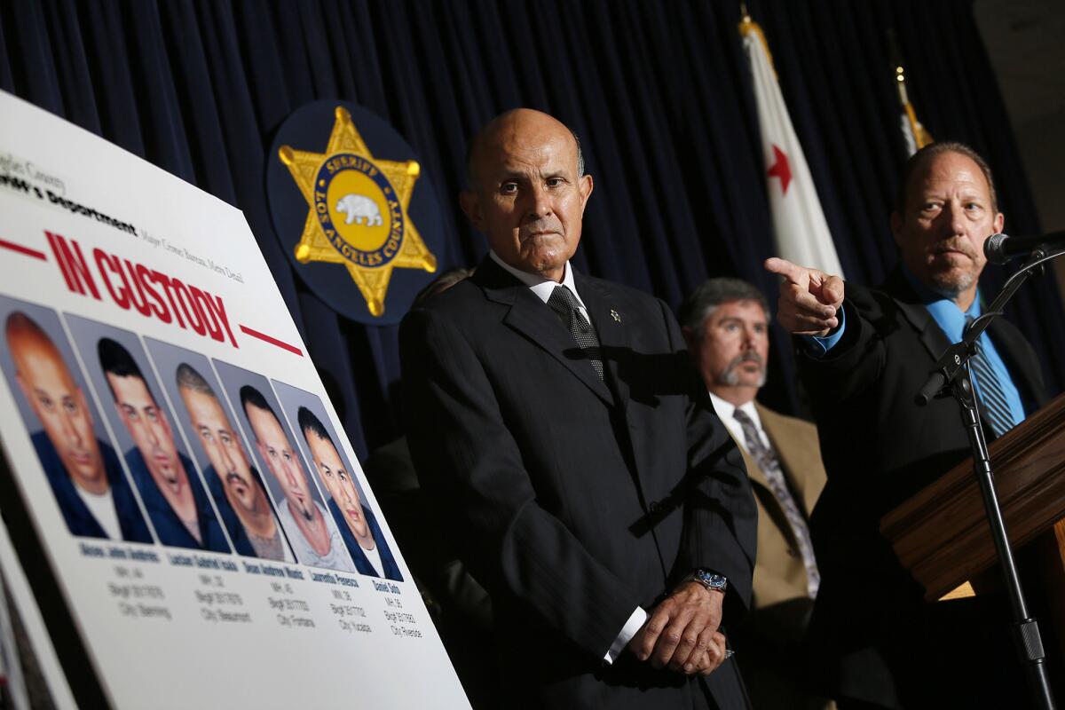 Los Angeles County Sheriff Lee Baca, left, looks at booking photos of suspects in a series of bank heists in the San Gabriel Valley. Five men were arrested last Friday in connection with the burglaries.