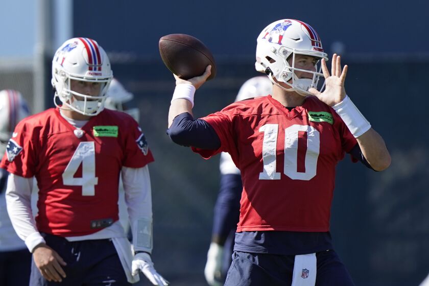 New England Patriots quarterback Mac Jones (10) winds up to pass as quarterback Bailey Zappe (4) looks on during an NFL football practice, Thursday, Oct. 6, 2022, in Foxborough, Mass. (AP Photo/Steven Senne)