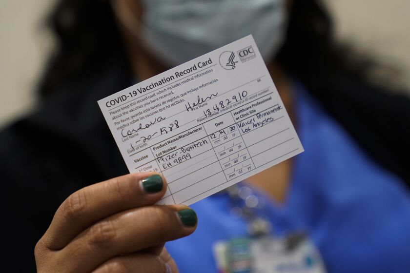 Nurse Helen Cordova shows her vaccination record card after receiving the Pfizer-BioNTech COVID-19 vaccine at Kaiser Permanente Los Angeles Medical Center in Los Angeles, Monday, Dec. 14, 2020. (AP Photo/Jae C. Hong)