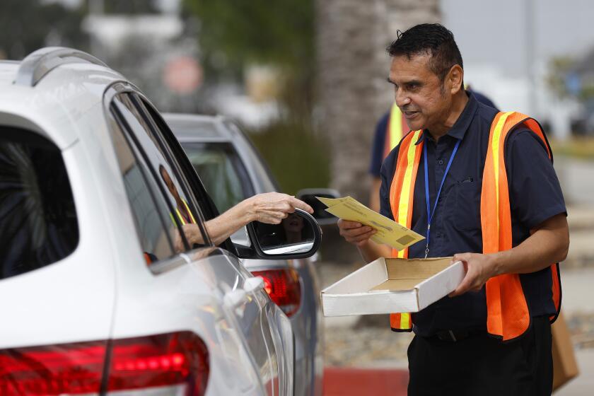 SAN DIEGO, CA - JUNE 7: Election worker George Araiza takes a ballot from a voter on Election Day at the San Diego Registrar of Voters on Tuesday, June 7, 2022. (K.C. Alfred / The San Diego Union-Tribune)