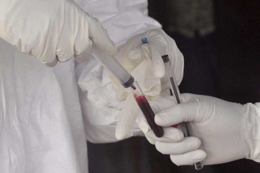 Health workers collect a blood specimen from a child on June 30 to test for Ebola in an area on the outskirts of the Liberian capital, Monrovia, where a 17-year-old boy died of the virus.