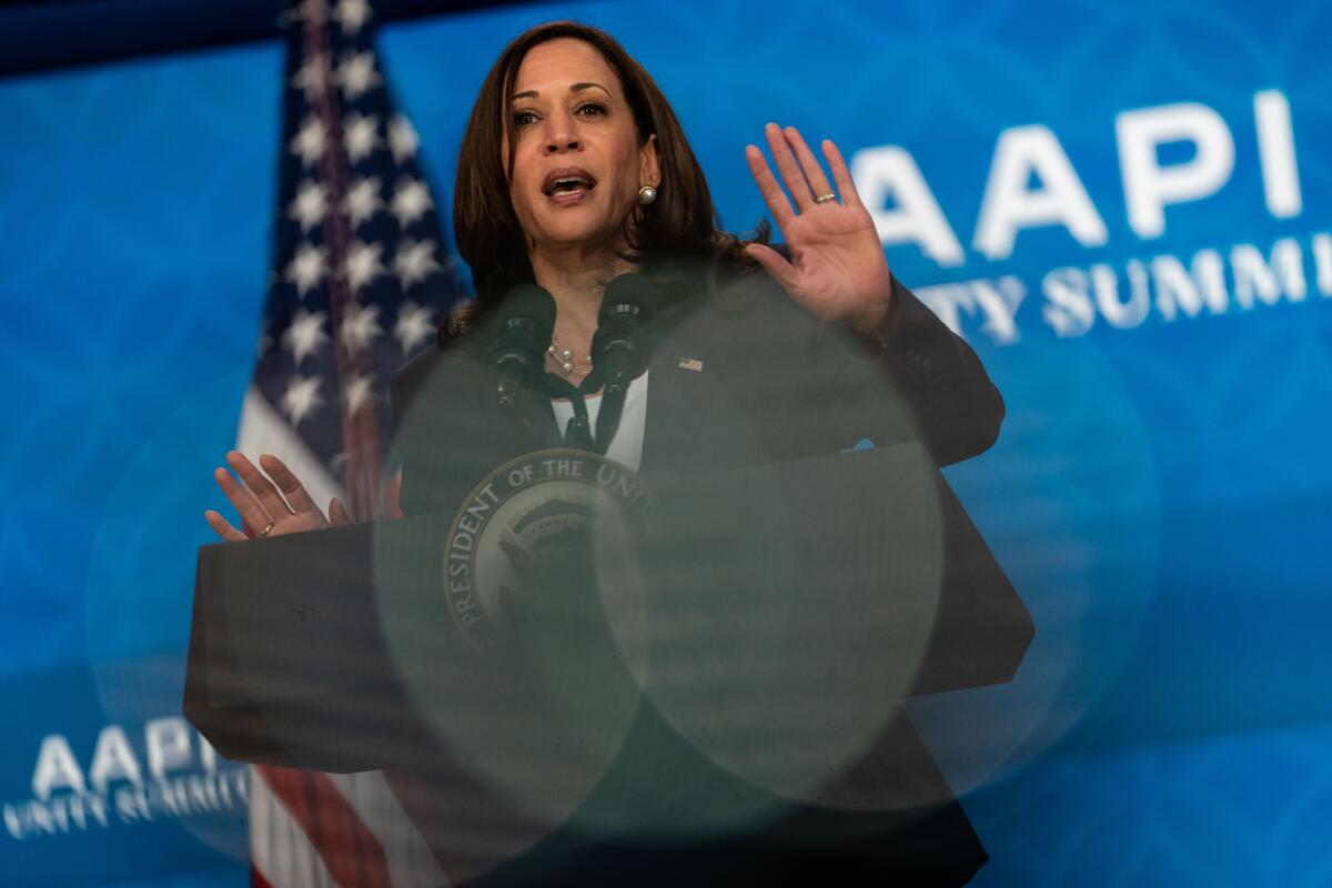  Vice President Kamala Harris speaks, with a U.S. flag and the words AAPI Unity Summit in the background

