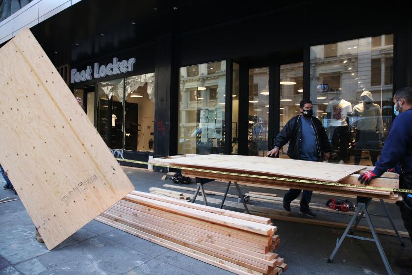 LOS ANGELES, CA - OCTOBER 28: Crews work to clean-up damage at a Foot Locker on Broadway from people who were out after the Dodgers won the world series in downtown on Wednesday, Oct. 28, 2020 in Los Angeles, CA. Last night, Los Angeles police declared unlawful assemblies in downtown and Echo Park to clear people out. (Dania Maxwell / Los Angeles Times)