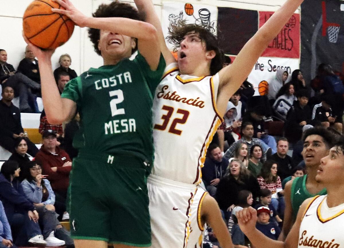 Costa Mesa's Dylan Dunbar (2) drives to the basket against Estancia's Miles Dodge (32) during Friday night's game.