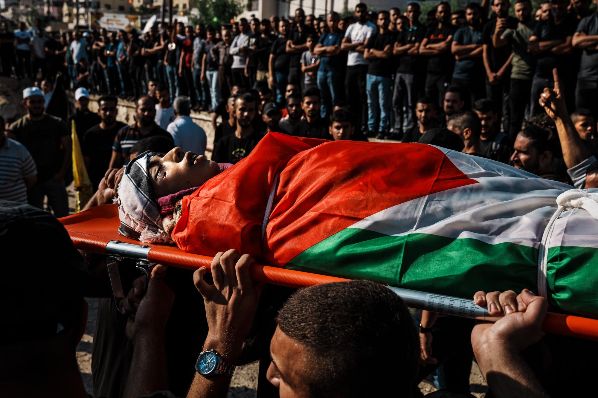 Mourners carry the nine bodies of thirteen Palestinians killed in an Israeli assault on the Nour Shams refugee camp.