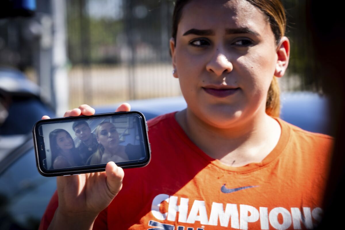 Stacey Sarmiento holds a photo up of her posing with her friend, Rudy Pena, who died in a crush of people at the Astroworld music festival in Houston. (AP Photo/Robert Bumsted)