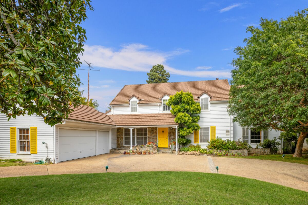 A white house with yellow accent doors and a bright green grass lawn