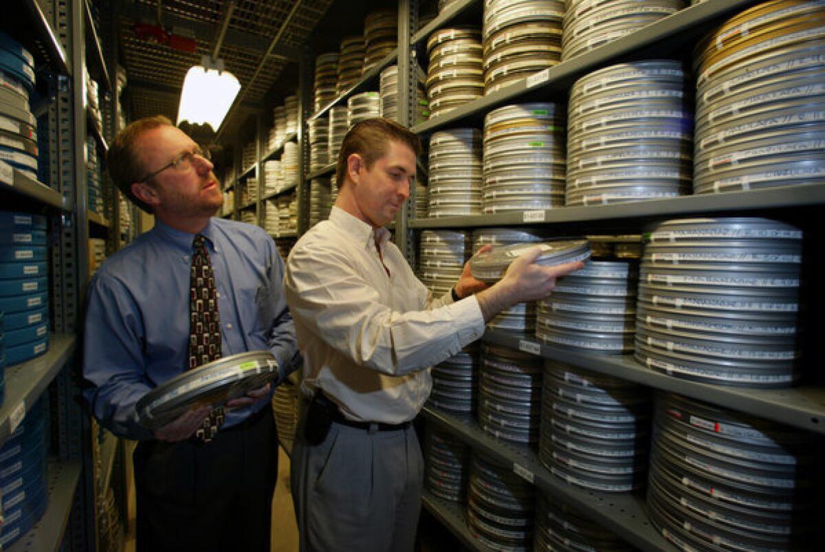 Ric Robertson, left, in the Academy Film Archive with a fellow academy employee. Robertson will step down from his role as COO, effective immediately.