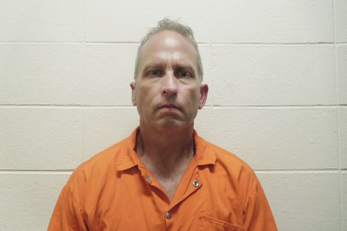 A booking photo of a man in an orange jumpsuit