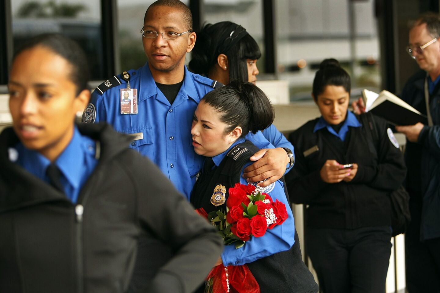 Transportation Security Administration agents embrace in front of Terminal 3 at LAX on Monday. Three days after a fellow agent was killed and several others wounded.