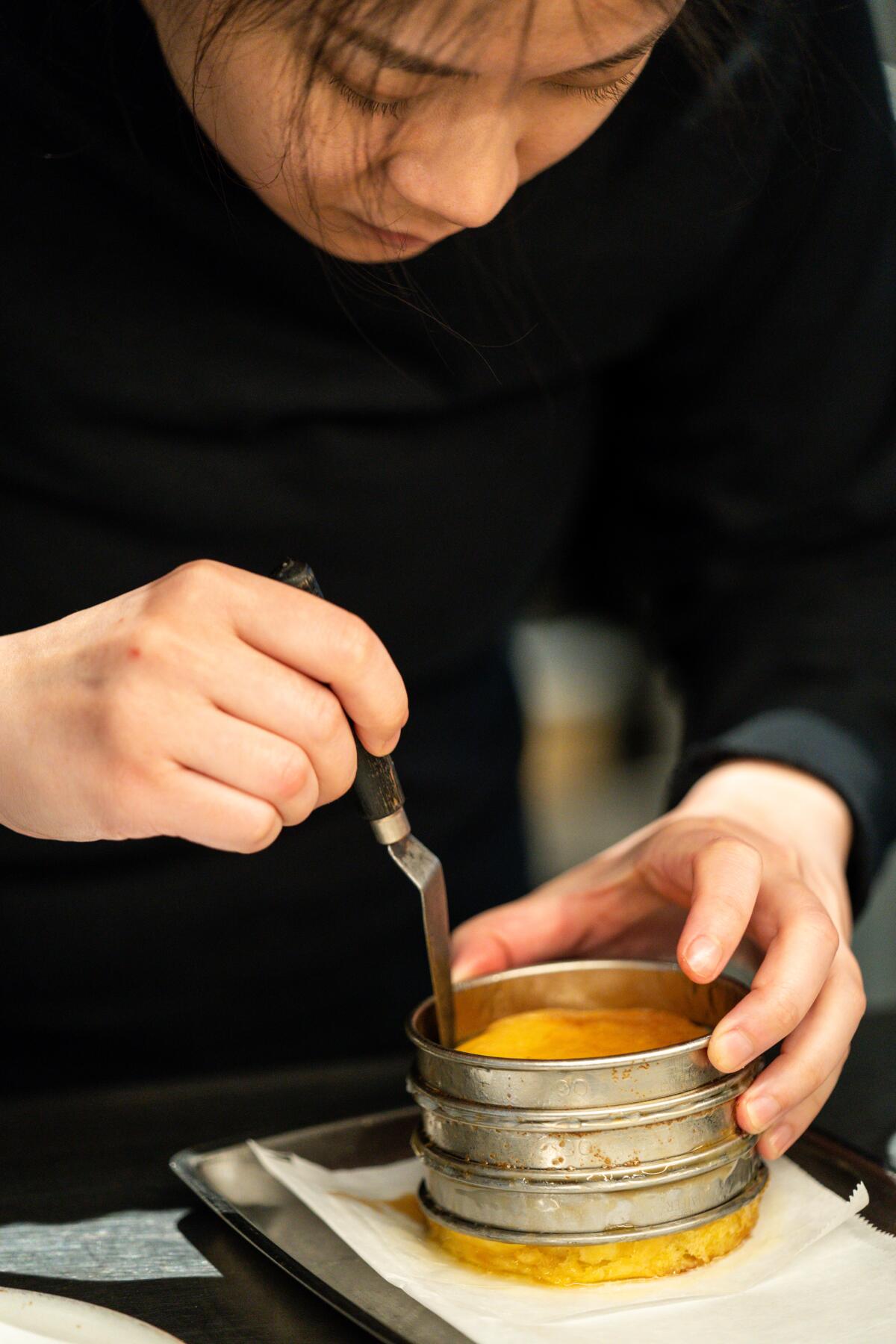 Dyan Ng runs a tool along the inside of the mold to release the cooked brioche. 