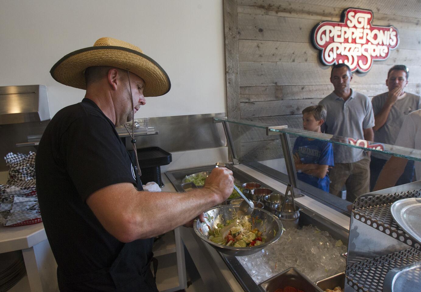 Co-owner Stan Frazier makes a salad during the grand reopening of Sgt. Pepperoni's Pizza Store on Friday.