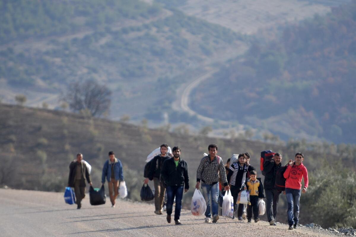 Syrian refugees walk on the side of a road after crossing the border into Turkey in 2014.