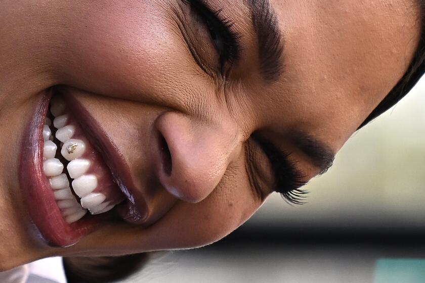 Los Angeles, California February 23 2022: New Sparks player Liz Cambage laughs as she sports an "LA" symbol on her tooth during a press conference to announce her signing with the team outside Crypto.com Arena Wednesday. (Wally Skalij/Los Angeles Times)