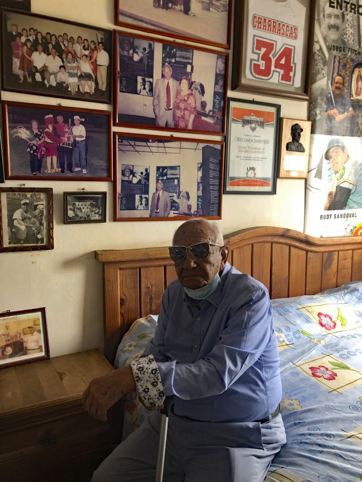 Pedro “Charrascas” Ramírez sits in his home next to photos of his family and baseball memorabilia. 2022.