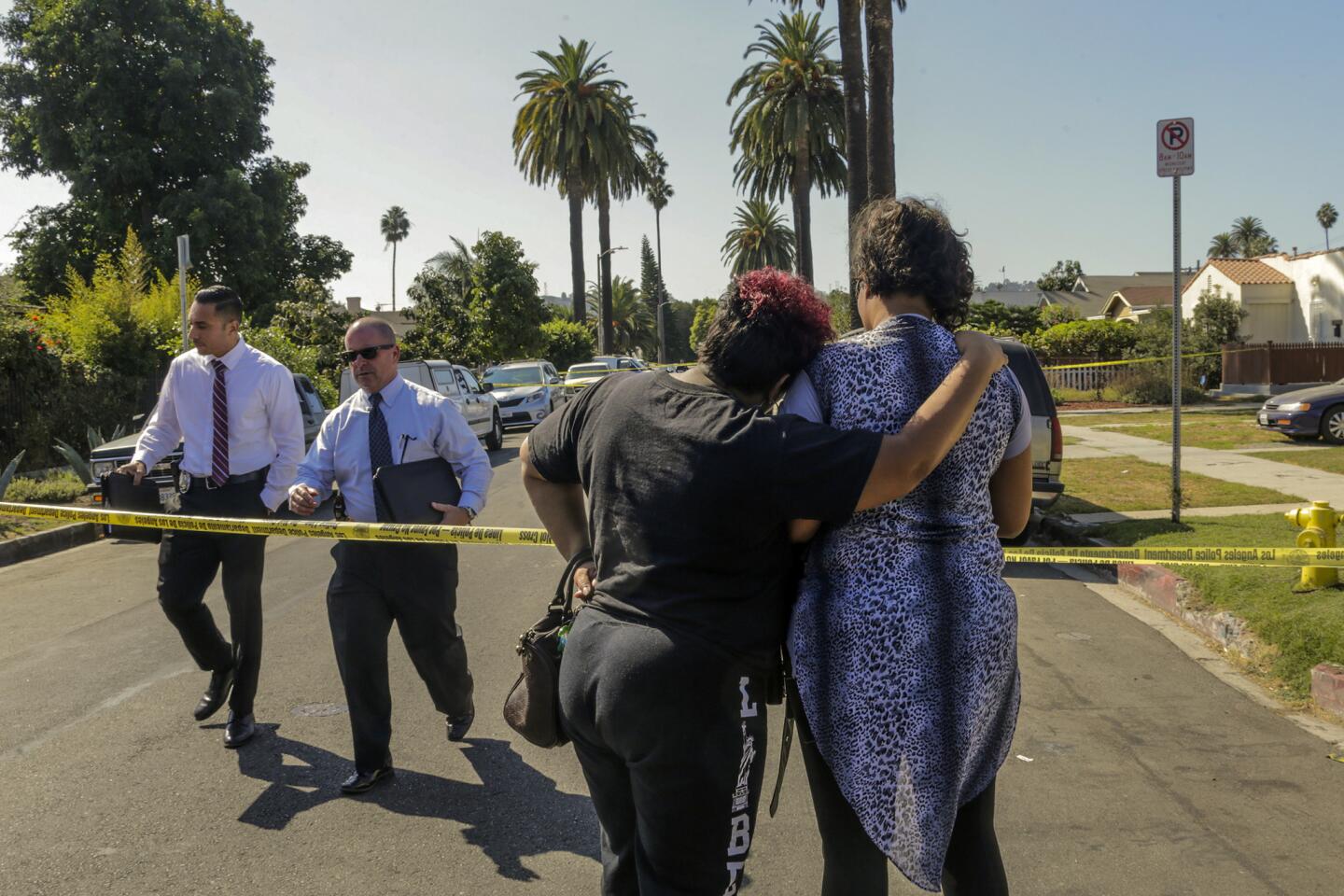 Detectives pass two women looking at the scene of a shooting in the West Adams district.