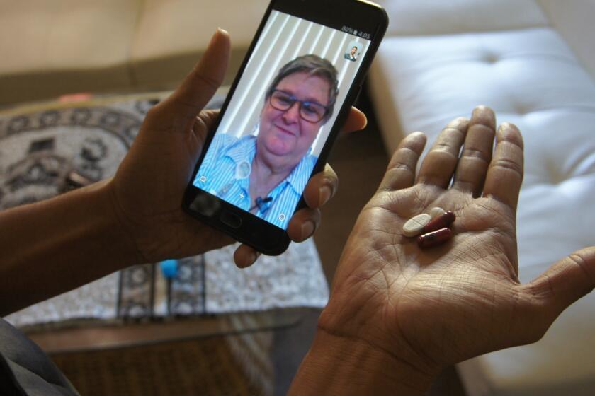 In this March 15, 2018 photo, public health nurse Peggy Cooley of the Tacoma-Pierce County Health Department, seen on the phone screen, uses Skype video to remotely monitor a patient taking antibiotics for tuberculosis at home in Lakewood, Wash. Researchers are testing how well smartphone apps that monitor pill-taking work when medication matters. Experts praise the efficiency, but some say the technology raises privacy and data security concerns. (AP Photo/Manuel Valdes)