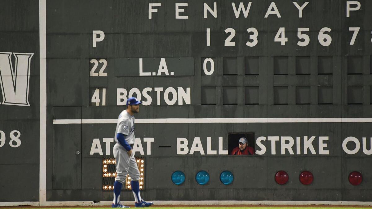 With a Fenway Park scoreboard handler looking on, the Dodgers' Chris Taylor gets into position during the first inning.