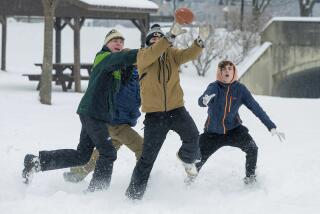 Liam McGreevy, left, Lucas Acerenza and Porter Jones play football in the snow at Baker Park Friday, Jan. 19, 2024 in Frederick, Md. The three Frederick High School students had the day off as Frederick County schools were closed. (Ric Dugan/The Frederick News-Post via AP)