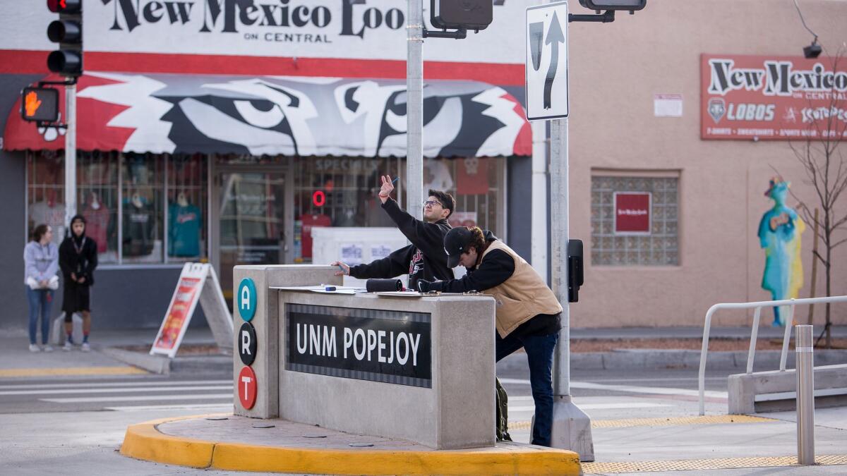 Architecture students use a non-functioning bus stop on Albuquerque's Central Avenue to sketch a building.