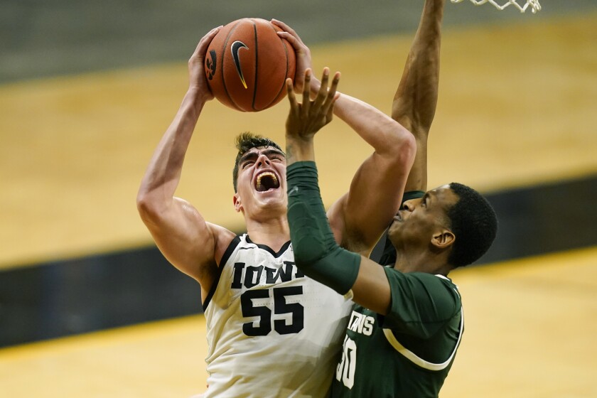 FILE - Iowa center Luka Garza (55) drives to the basket against Michigan State forward Marcus Bingham Jr., right, during the second half of an NCAA college basketball game in Iowa City, Iowa, in this Tuesday, Feb. 2, 2021, file photo. Garza was named The Associated Press men's basketball player of the year on Thursday, April 1. (AP Photo/Charlie Neibergall, File)