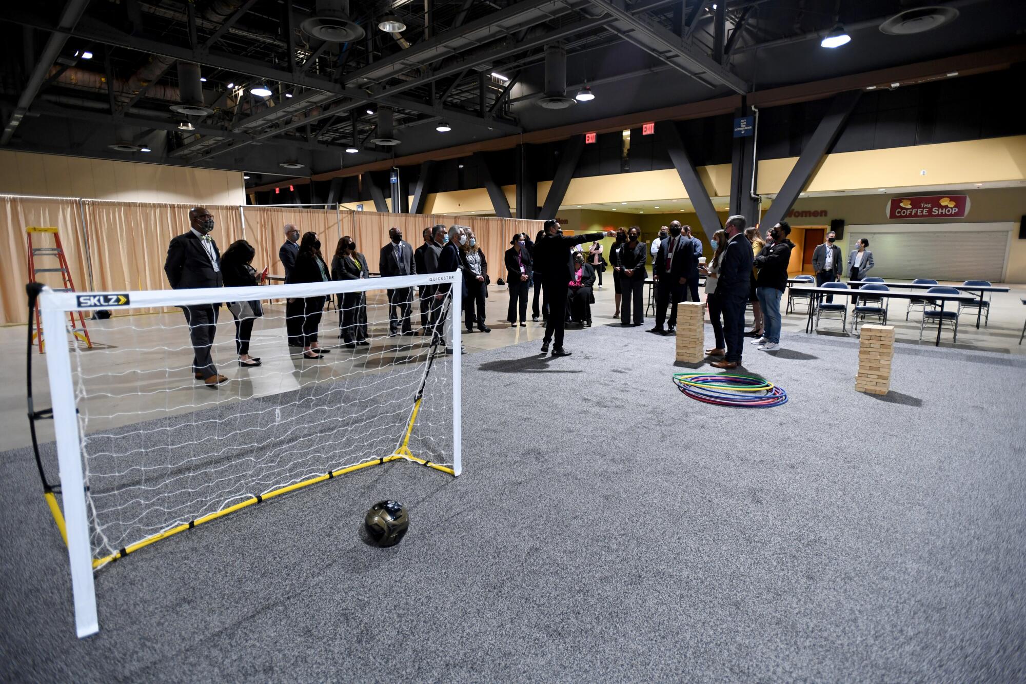 People stand in a recreation area with hula hoops, a soccer net and ball and tables.