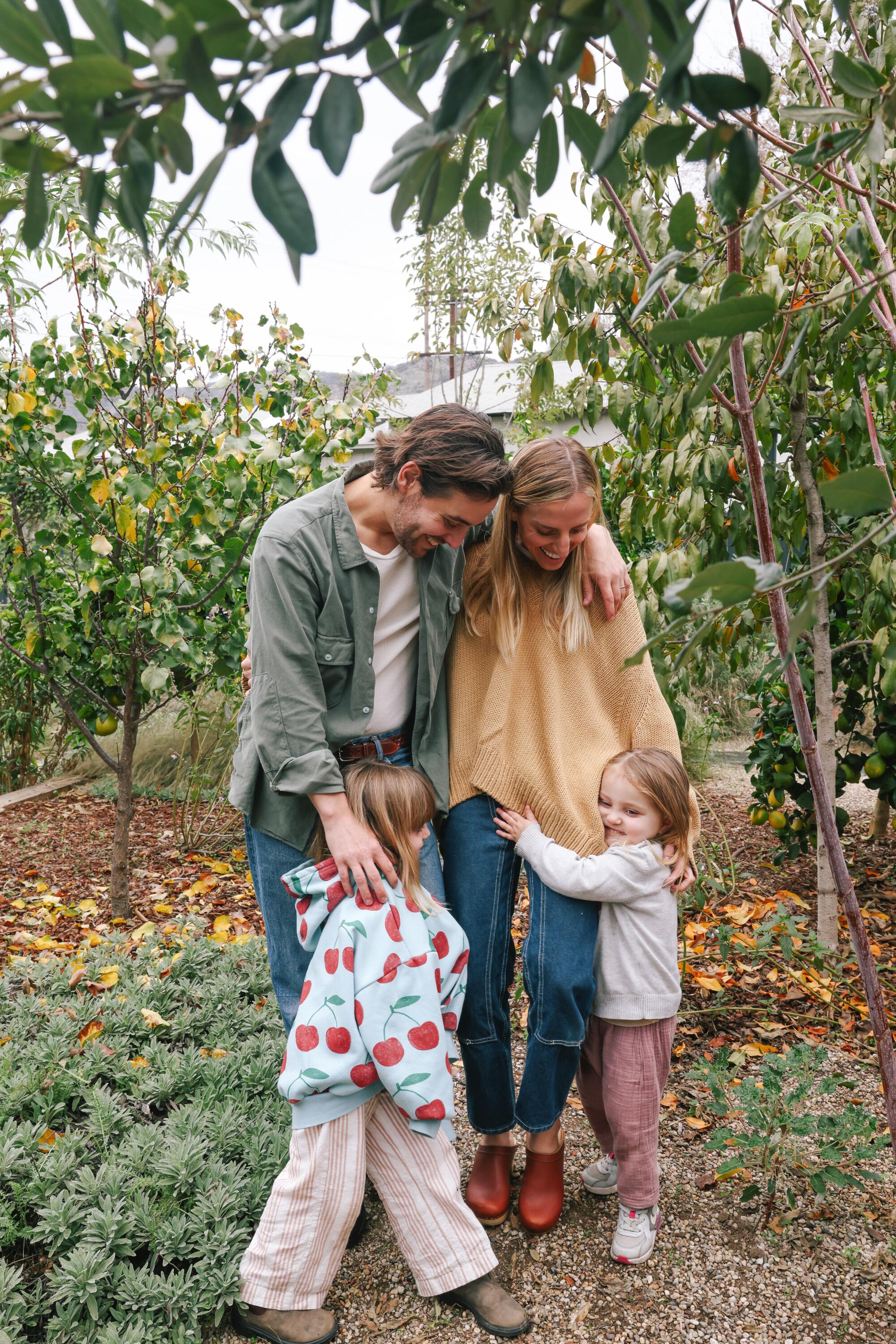 A couple and their two young daughters stand in a citrus grove 