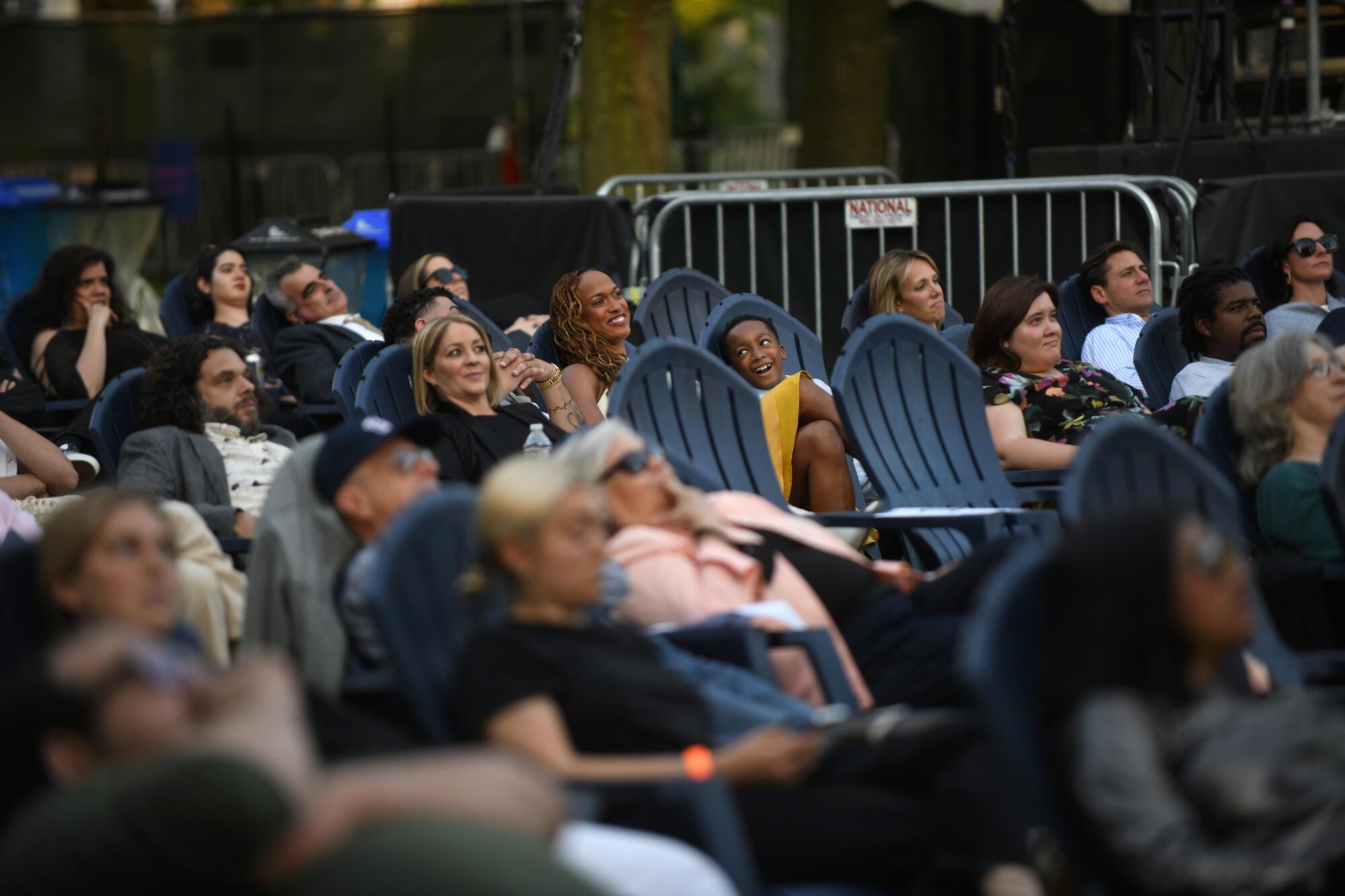 An audience in Adirondack chairs see a movie