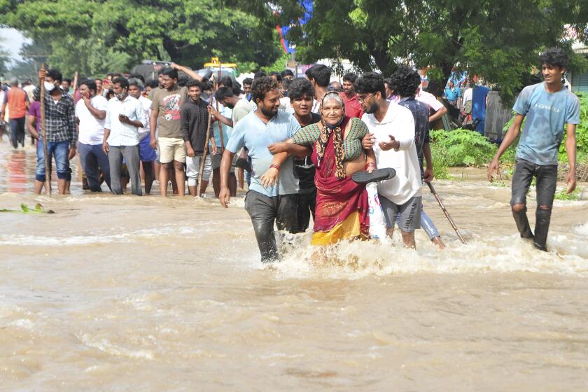 People wade through a flooded street in Nellore, in the southern Indian state of Andhra Pradesh, Saturday, Nov. 20, 2021. More than a dozen people have died and dozens are reported missing in Andhra Pradesh after days of heavy rains, authorities said. (AP Photo)