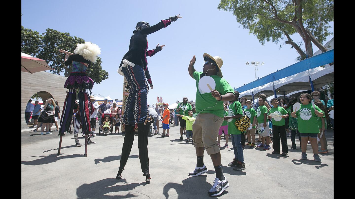 A member of the Dragon Knights Stilt theater dances with a youth camp counselor as the gates open for the "Farm, Fresh, Fun" 2017 OC Fair on Friday.