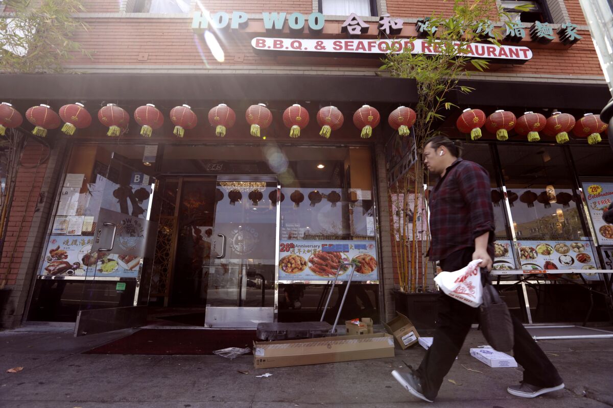 A pedestrian walks past Hop Woo restaurant on Broadway in Chinatown on May 3.