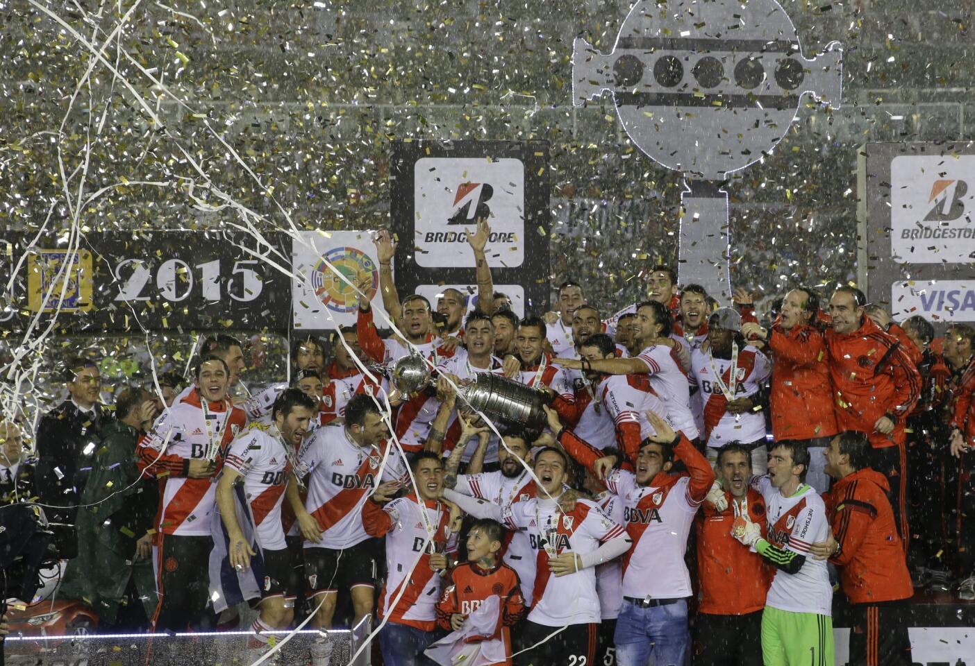 Argentina's River Plate players and staff hold the trophy aloft while they celebrate winning the the Copa Libertadores final soccer match against Mexico's Tigres in Buenos Aires, Argentina, Thursday, Aug. 6, 2015. River defeated Tigres 3-0 and became the tournament champions. (AP Photo/Ivan Fernandez)